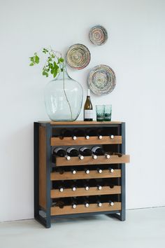 a wine rack with several bottles on it next to a vase and plate wall hangings