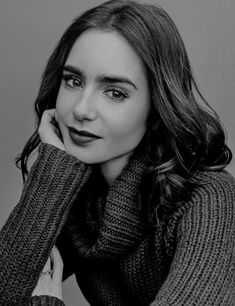 a black and white photo of a woman with her hand on her chin wearing a scarf