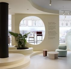 an office with circular windows and seating area in front of the window is a plant