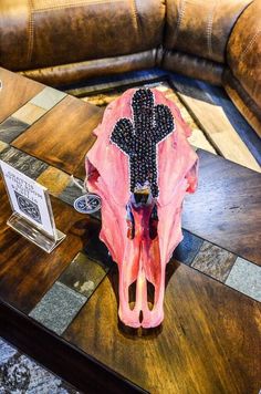 a pink cow skull sitting on top of a wooden table next to a leather couch