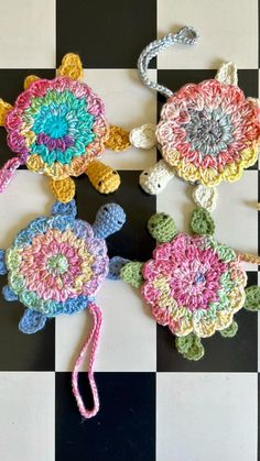 two crocheted flowers sitting on top of a black and white checkered floor