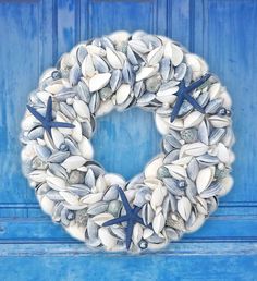 a wreath made out of seashells and starfish on a blue door