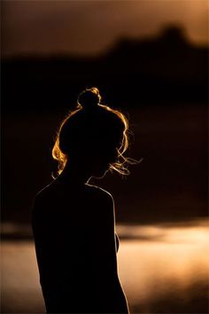 a black and white photo of a woman with her hair blowing in the wind at night