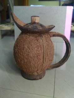 a brown vase sitting on top of a white tile floor next to a wooden handle