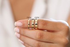 a woman's hand holding two gold rings