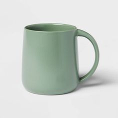 a green mug sitting on top of a white table