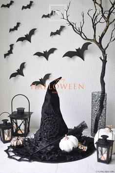 halloween decorations with bats and pumpkins on a table in front of a white wall