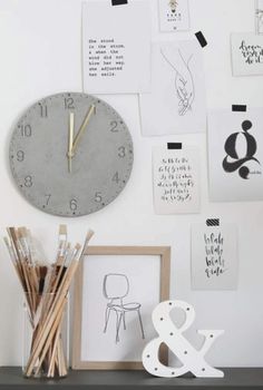 there is a clock on the wall next to pictures and pencils in front of it