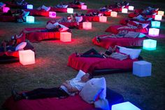 people are laying on bean bags in the grass with glowing lights around them and reclining