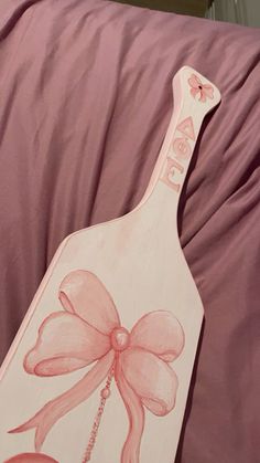 a wooden sign with a flower painted on it sitting on a pink bed sheet in front of a window