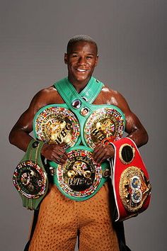 a man holding two boxing belts in his hands