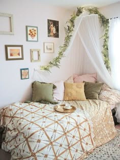 a bed with a white canopy over it in a bedroom next to pictures on the wall