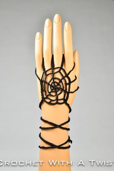 a mannequin's hand is adorned with black string and beaded beads