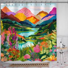 a bathroom with a shower curtain that has colorful flowers on it and mountains in the background