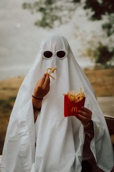 a person in a ghost costume eating french fries