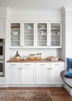 a kitchen with white cabinets and wooden counter tops, along with an area rug on the floor