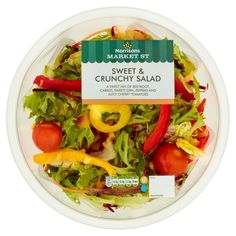 a salad in a plastic container on a white surface with a green and yellow label