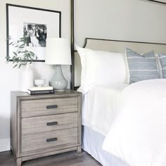 a bedroom with a bed, two nightstands and pictures on the wall above it