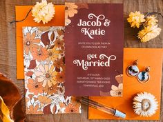 an orange and brown wedding stationery with flowers on it, along with other items