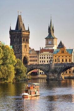 there is a boat on the water in front of some buildings and a bridge with a clock tower