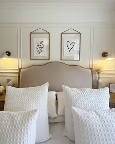 two framed pictures hang on the wall above a bed with white sheets and pillows in a bedroom