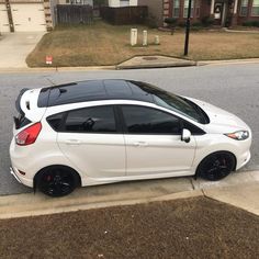 the white car is parked on the side of the street