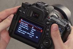 a person holding up a camera with the screen showing it's settings and instructions