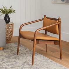 a wooden chair sitting on top of a hard wood floor next to a vase filled with flowers