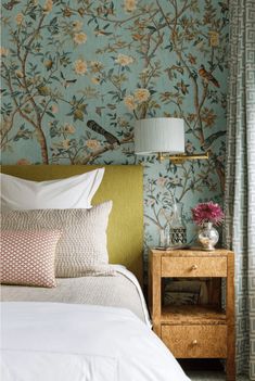 a bedroom with floral wallpaper and green headboard