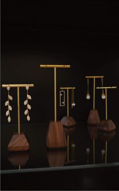 three pairs of earrings are on display in a black room with gold posts and wood bases