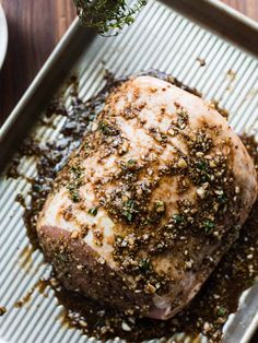 the meat is covered with herbs and seasoning on it's side, sitting on a baking sheet