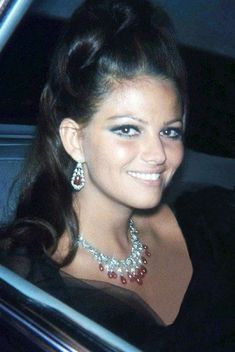 a woman sitting in a car wearing a necklace and earring on her left hand