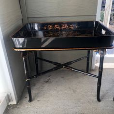 a black and gold tray sitting on top of a wooden table next to a door