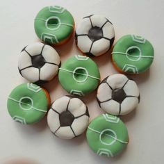 six green and white frosted donuts with soccer balls on them, sitting next to each other