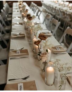 a long table is set with candles and flowers in vases on the tables, along with place settings