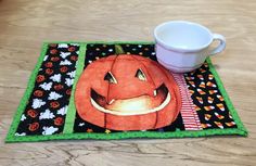 a pumpkin placemat with a coffee cup on it next to a mug cozyie