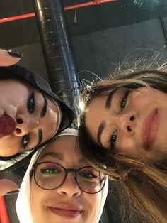 three young women are posing for the camera with their faces painted red and black,