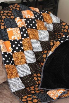 a black and orange quilt with white polka dots on the edges is sitting on a couch