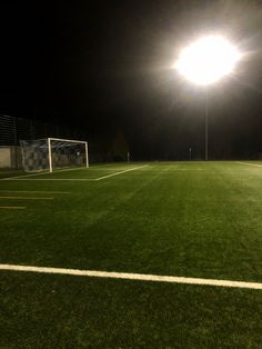 an empty soccer field at night with the lights on and no one in it yet