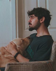 a man sitting in a chair with his head on a dog's face,