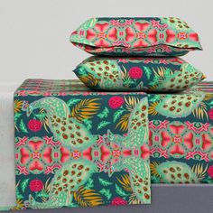 three pillows are stacked on top of each other in front of a bed with colorful patterns