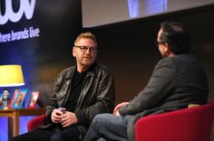 two men sitting in chairs talking to each other