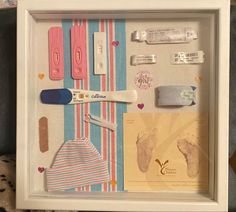 a shadow box with baby items in it on a shelf next to a teddy bear