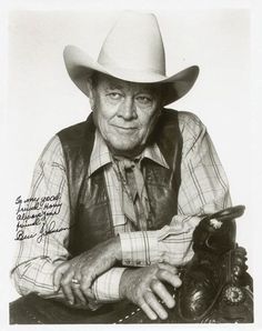 an old photo of a man wearing a cowboy hat with his hand on a shoe