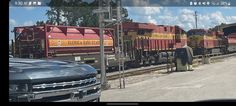 a man standing in front of a train on the tracks next to a car and truck