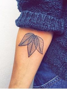 a woman's arm with a tattoo on it that has an image of a leaf