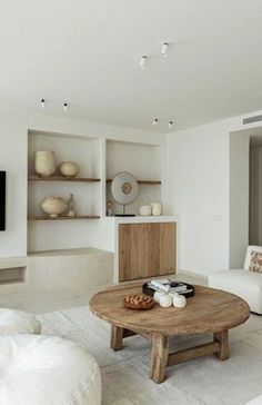 a living room filled with furniture and a flat screen tv mounted on the wall above a wooden coffee table