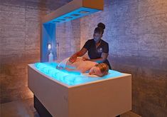 a woman getting a back massage in a spa room with blue lights on the walls