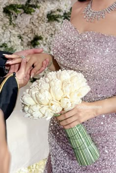 the bride and groom are exchanging hands at their wedding ceremony in front of white flowers