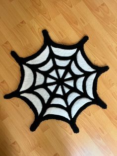 a black and white spider web rug sitting on top of a wooden floor